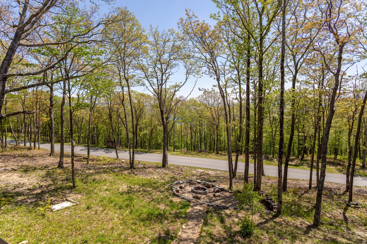 A serene backyard scene with a stone fire pit surrounded by trees and natural beauty, perfect for evening gatherings, s'mores, and storytelling under the stars. The setting radiates peace and togetherness as dusk falls.