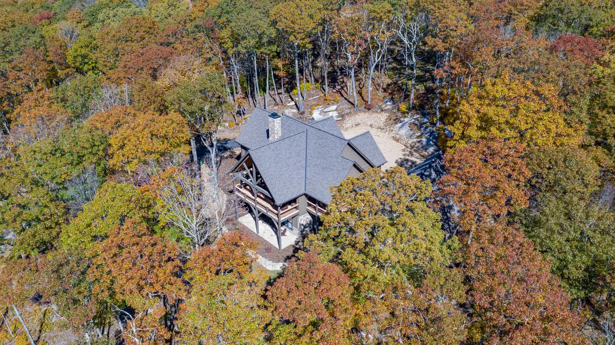 This exterior shot presents the rustic house amid vibrant autumn foliage and mature trees, evoking the changing mountain seasons. The calm environment suggests opportunities for hiking, nature walks, and quiet moments appreciating the view.