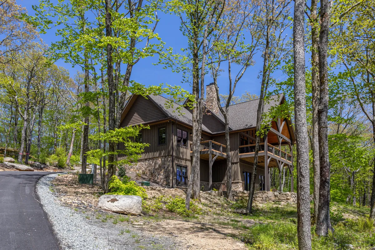 This image showcases the property’s exterior, featuring the house nestled among tall trees with a stone pathway leading up to the entrance. The tranquil setting is enveloped in nature, highlighting the peaceful mountain surroundings and inviting guests to relax outdoors or begin explorations from the doorstep.