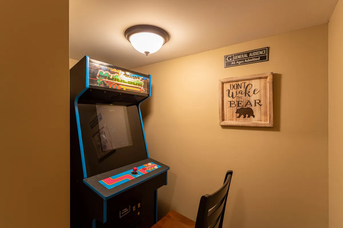 This image captures an arcade game machine in a cozy corner, accompanied by a decorative sign and a comfortable chair, creating an immediate sense of fun and nostalgia. The playful setup hints at the promise of classic arcade challenges and laughter-filled gaming sessions.