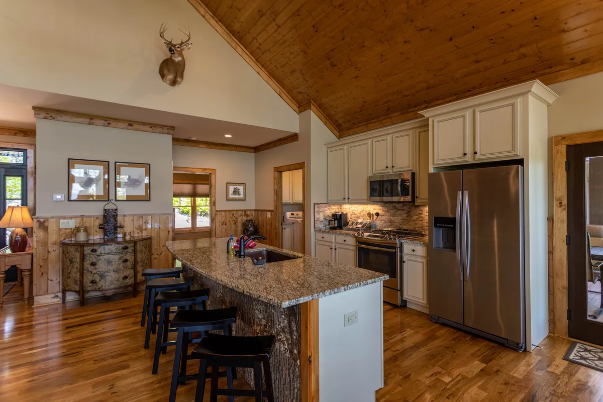 This image spotlights a kitchen with granite countertops, wooden cabinets, stainless steel appliances, antler decor, and bar stools—inviting both cooking and casual conversation. The design is rustic yet modern, perfect for meal prep and socializing.