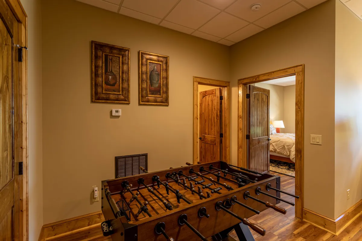 An interior shot of a friendly game space featuring a foosball table, framed artwork, and wooden doors, creating a laid-back and cheerful environment for rainy day fun and family competition.